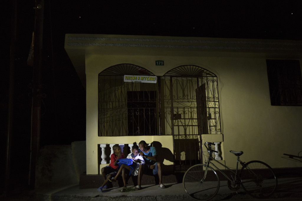 A group of friends in Coteaux, Haiti, share a flashlight to study and do homework. (Photo By: Garrett Hubbard)