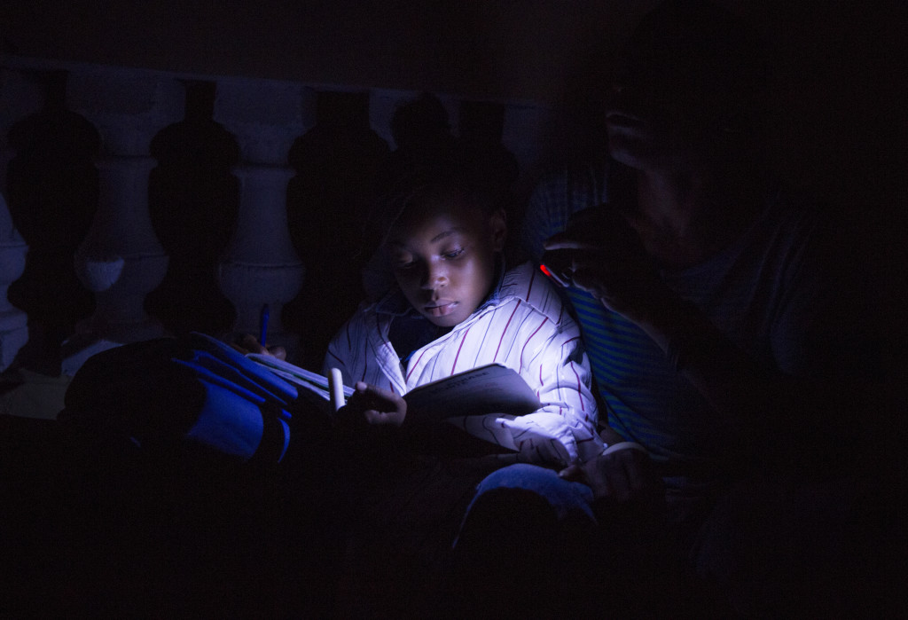A flashlight is the only source of light for a young boy doing his homework on the streets of Coteaux, Haiti. (Photo By: Garrett Hubbard)